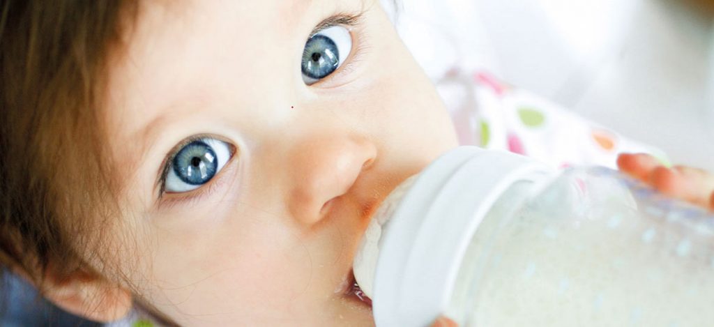 Ein Baby trinkt aufgewärmte Muttermilch aus einer Flasche