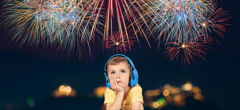 Kind trägt Gehörschutz und betrachtet ein Feuerwerk