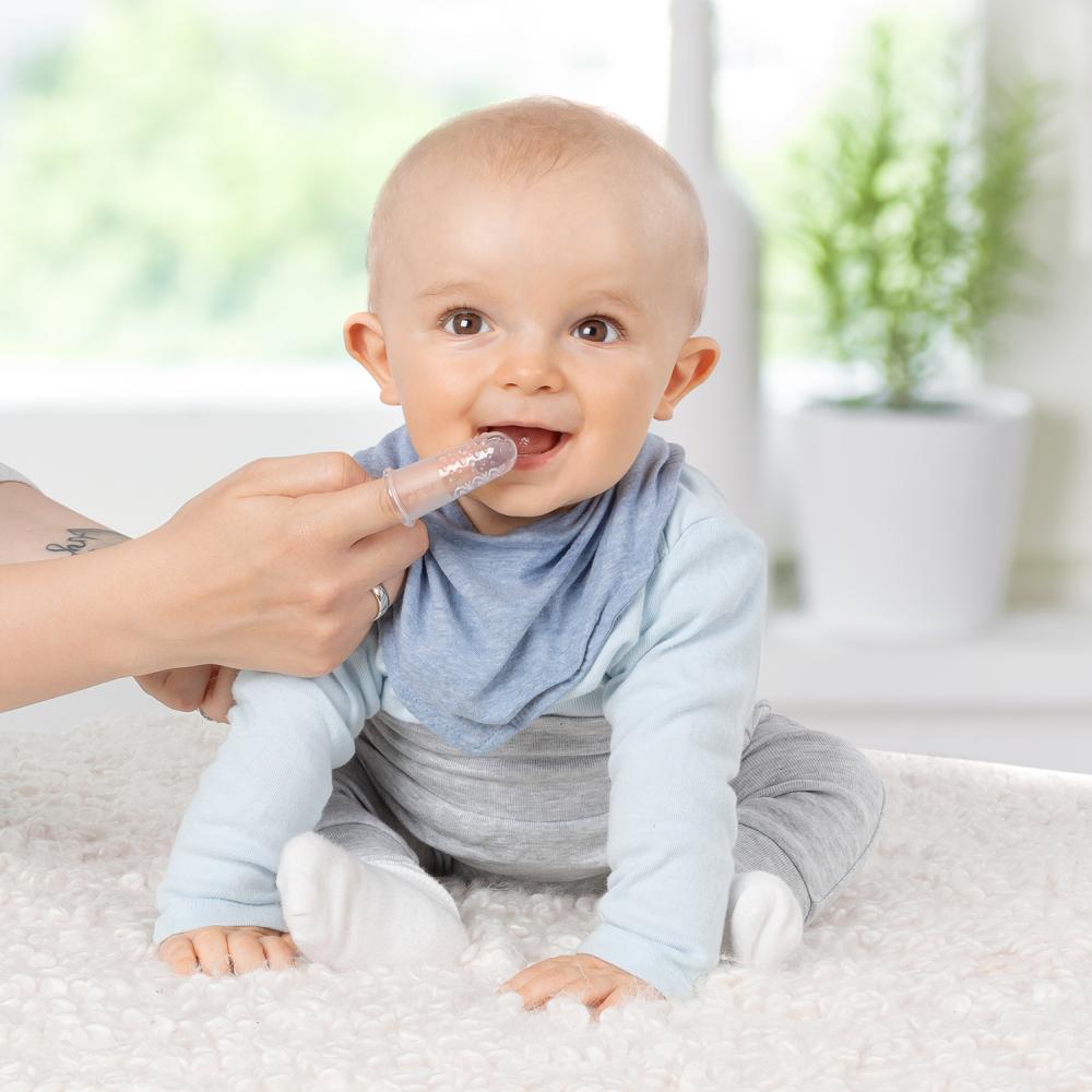 Baby bekommt die Zähne geputzt mit einer Fingerzahnbürste