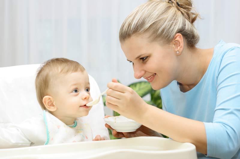 Mutter füttert Kind mit Babybrei