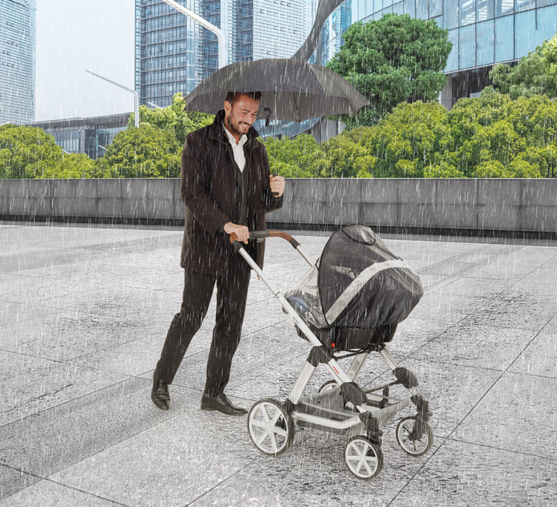 Vater geht mit seinem Kind im Kinderwagen spazieren, während es regnet