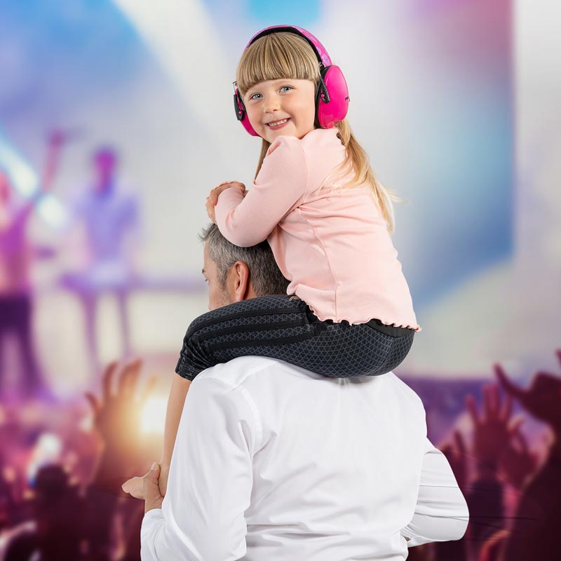 Kind bei einem Konzert sitzt auf den Schultern des Vaters und trägt Ohrenschützer