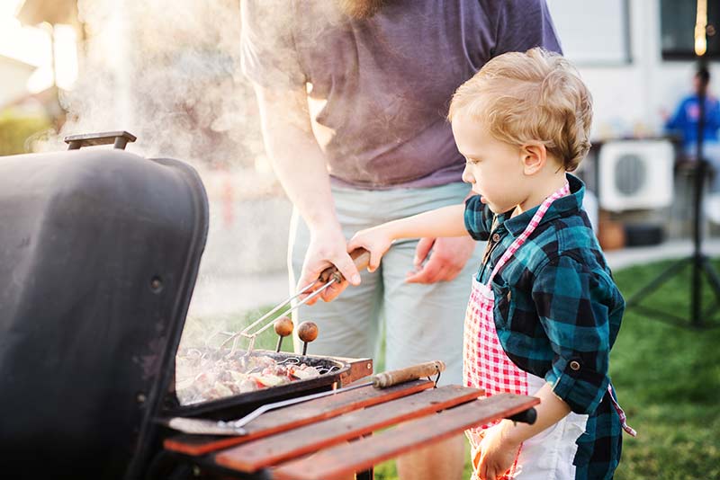 Kind hilft dem Papa beim Grillen