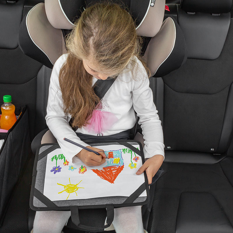 Kind sitzt im Kindersitz im Auto und malt