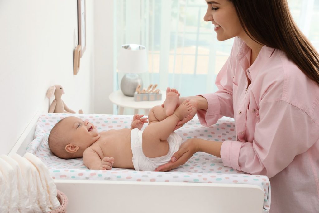 Mama wickelt ein lachendes Baby.