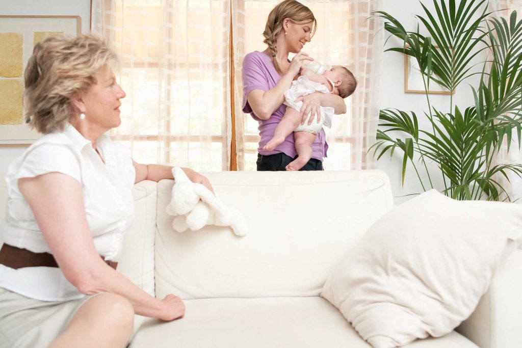 Oma beobachtet, wie Mama das Baby mit Fläschchen füttert.