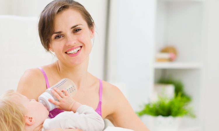 Lächelnde Mutter füttert Baby mit Fläschchen.